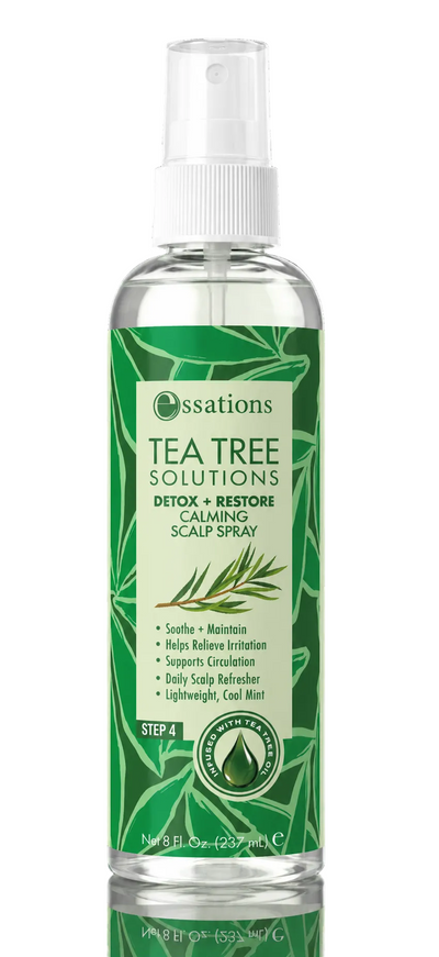 A bottle of Essations Tea Tree Solutions Calming Scalp Spray on a solid black background with a reflection below. The bottle is clear, showing the liquid inside, and features a prominent green label with white text and illustrations of tea tree leaves.